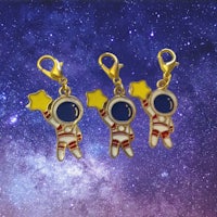 three astronaut charms with stars on them